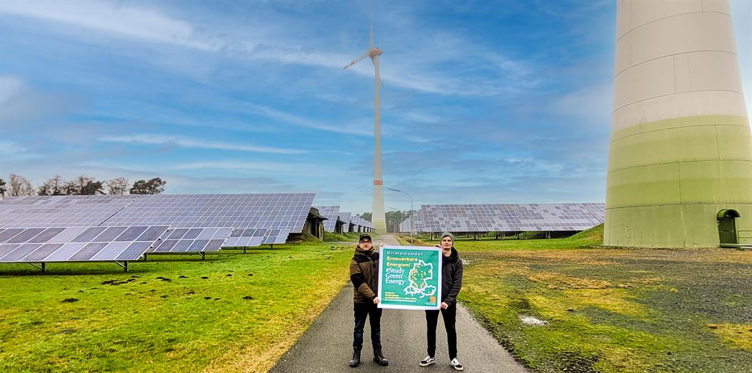 Zwei junge Männer stehen vor einer Windkraftanlage und halten ein Plakat hoch mit der folgenden Aufschrift: Klimawandel - Erneuerbare Energien! #StudyGreenEnergy Entdecke Studiengänge an Hochschulen in deiner Nähe auf www.stugygreenenergy.eu Deutsche Gesellschaft für Sonnenenergie